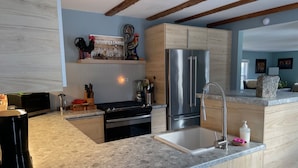 A modern kitchen with granite countertops, stainless steel appliances, and wooden cabinetry. - Relax on the South Shore, steps from 2 beaches, ocean views & hot tub. (East River Point)