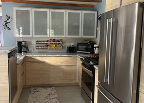 A modern kitchen with wooden cabinets, a stainless steel refrigerator, a microwave, and a stove.