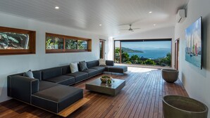 Un salon moderne avec un canapé d’angle, une table basse et une vue sur la mer.