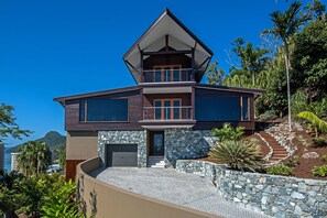 Une maison à deux étages avec une façade en pierre, un balcon et une vue sur l’océan.