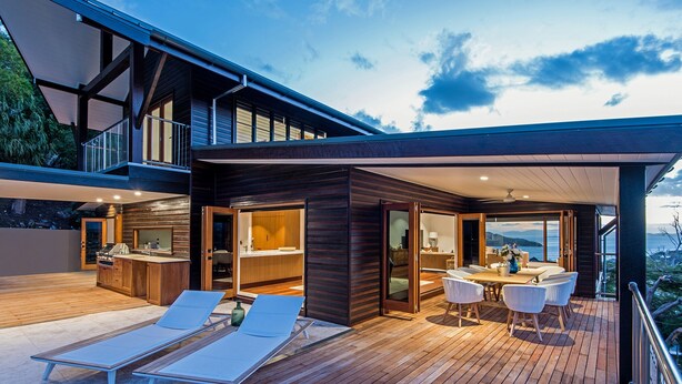 Une terrasse extérieure moderne, dotée de chaises longues, d’un espace repas et d’une cuisine.