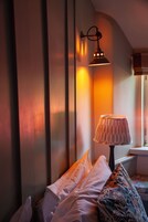 Um quarto com cama, almofadas, abajur e janela.