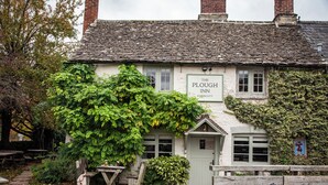 A traditional building with a sign reading 'The Plough Inn' and a green ivy-covered wall. - The Plough Inn (Lechlade)