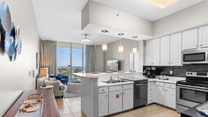 A modern kitchen with white cabinets, a central island, a microwave, and a stove. - Destin West Villa PH04 ~ Penthouse w /Hot Tub on Private Rooftop Terrace ~ Beach Views! (Fort Walton Beach)