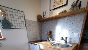 A compact kitchen with a wooden countertop, a sink, a small oven, and a trash bin. - Gîte La Ruchette (Sainte-Marguerite-sur-Duclair)