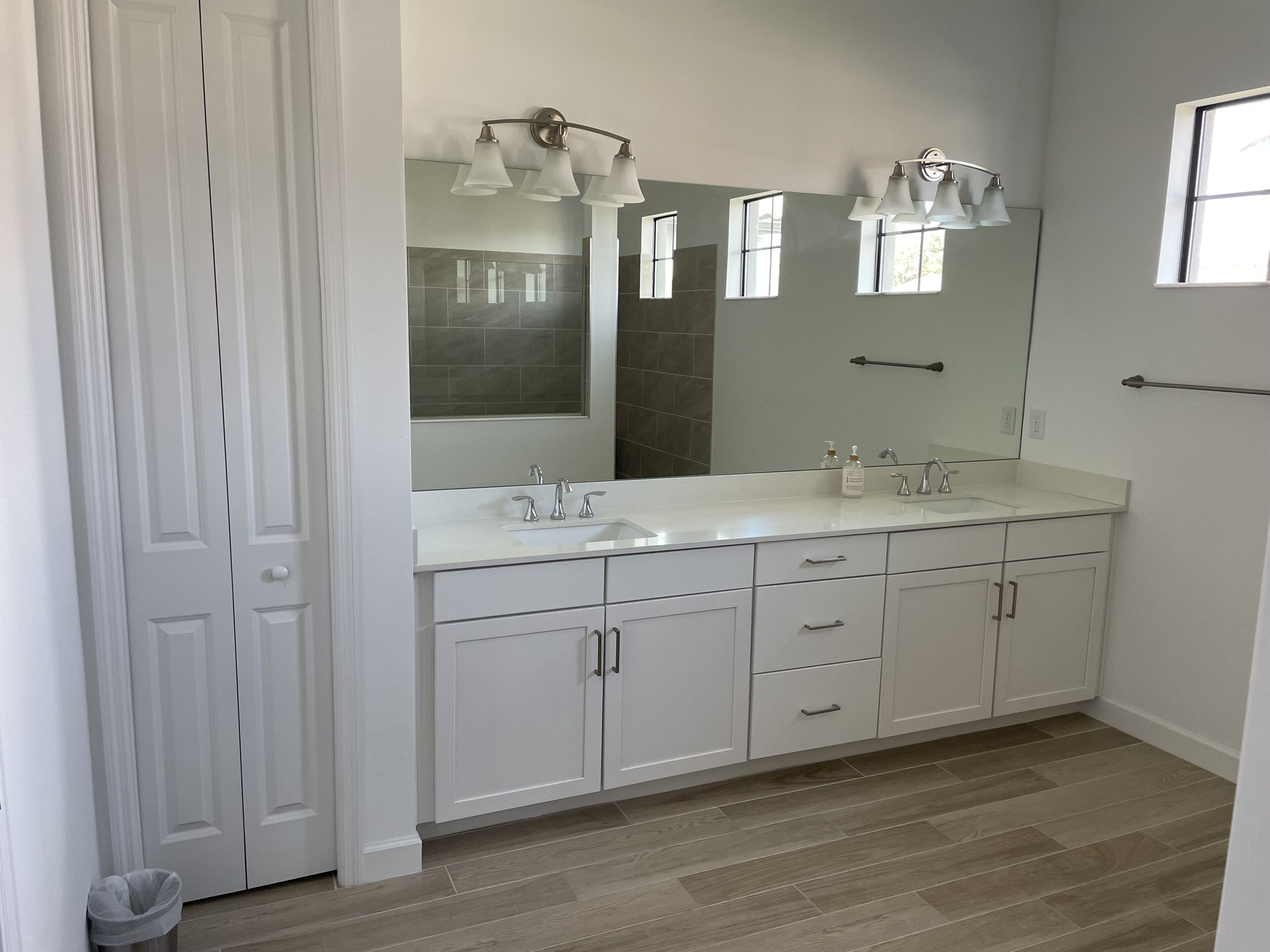 Un baño con lavamanos doble, un espejo grande y un perchero para toallas.