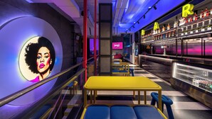 Eine moderne Bar mit Neonleuchtreklame, Sitzgelegenheiten und einer Theke mit Flaschen.