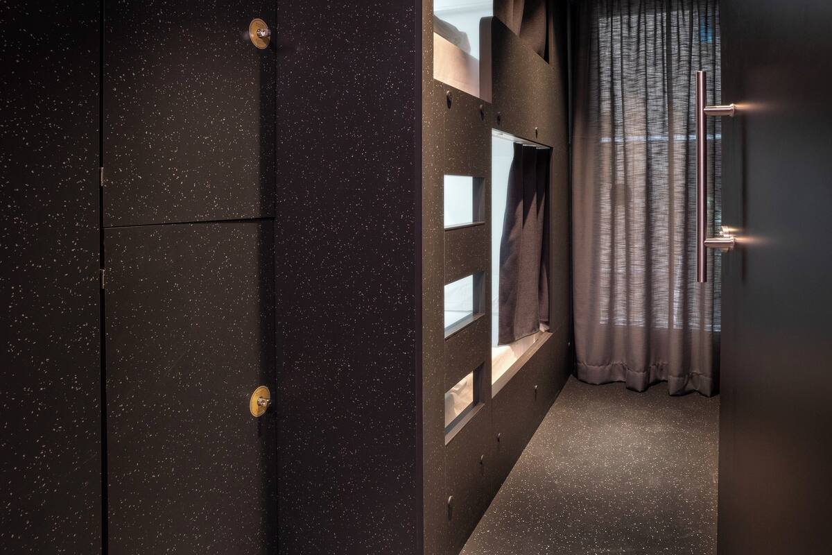 Un pasillo estrecho con un muro salpicado de estrellas, una ventana con vistas y una cortina.