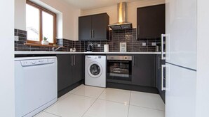 Una cocina moderna con lavavajillas, lavadora, horno y cocina integrada.