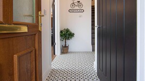 Un pasillo con baldosas estampadas, una planta en maceta y un letrero en la pared que dice "PARF'S PLACE" con una ilustración de una bicicleta.