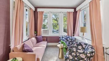 A cozy room with a pink sofa, a floral armchair, and a small side table.