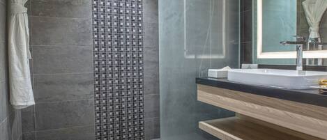 A modern bathroom with a glass shower enclosure, a large mirror, and a wooden vanity.