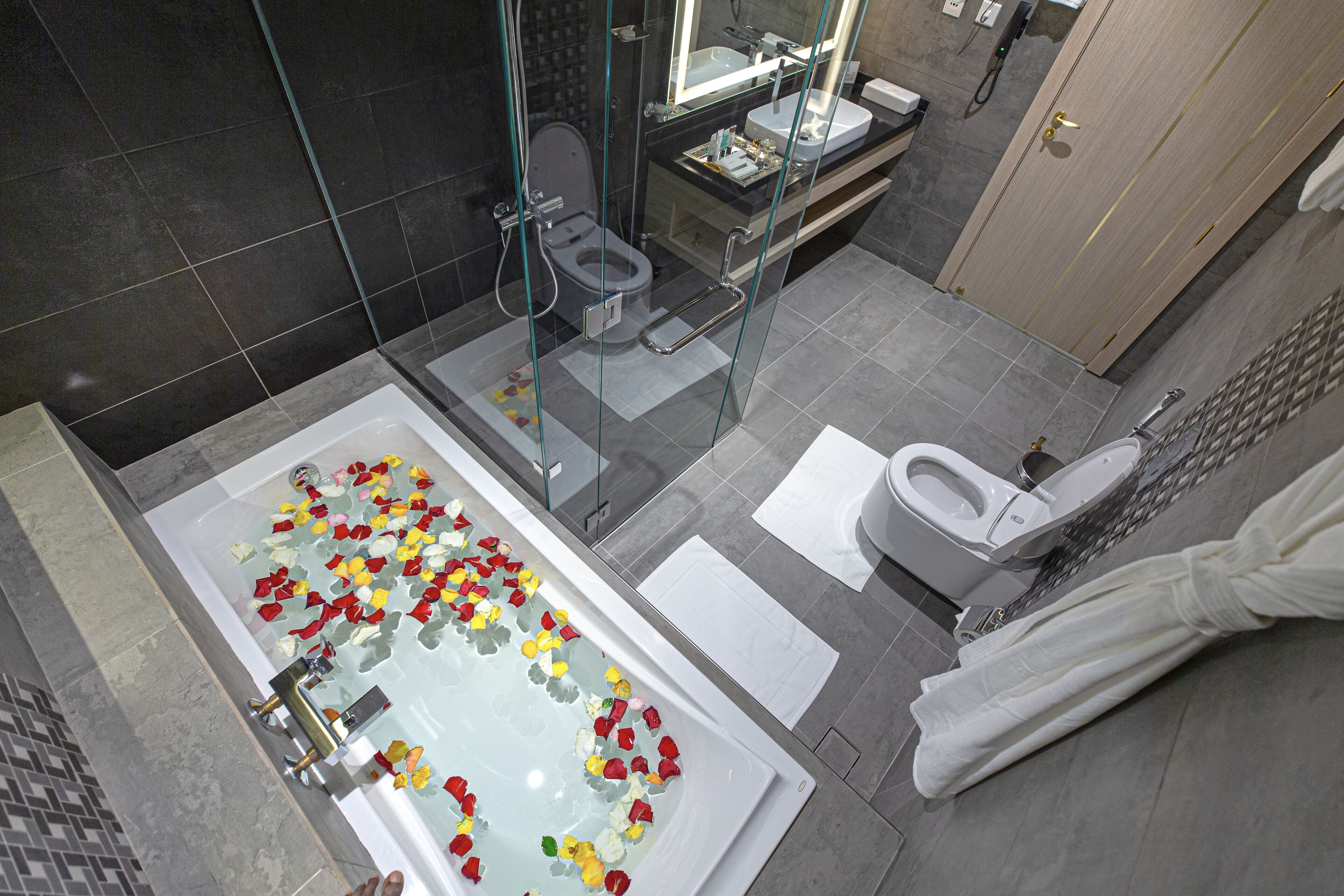 Un baño moderno con bañera de hidromasaje con mampara de vidrio, inodoro separado y zona de ducha.