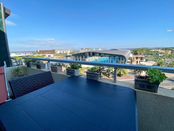 A balcony with a view of a modern building and a pool. - Appartement 4e Étage 300 m Plage (Sète)