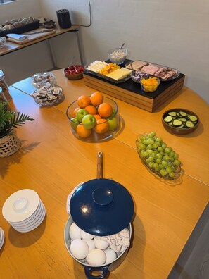 Ein Frühstücksbuffet mit verschiedenen Speisen, darunter Obst, Käse und Eier.