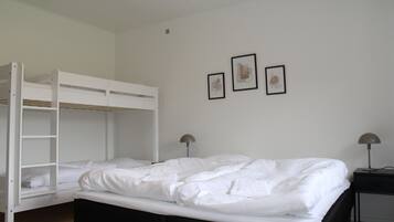A bunk bed room with a black headboard, white bedding, and two bedside lamps.