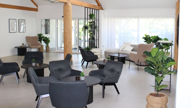 Ein geräumiger, moderner Loungebereich mit bequemen Sitzgelegenheiten, großen Fenstern und einem minimalistischen Design.