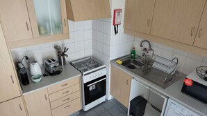 Une cuisine compacte équipée d’une cuisinière à gaz, d’un grille-pain, d’une bouilloire, d’un évier et d’un lave-linge.