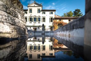 Ein Gebäude mit Spiegelung in einem Gewässer, mit Balkon und Statue.