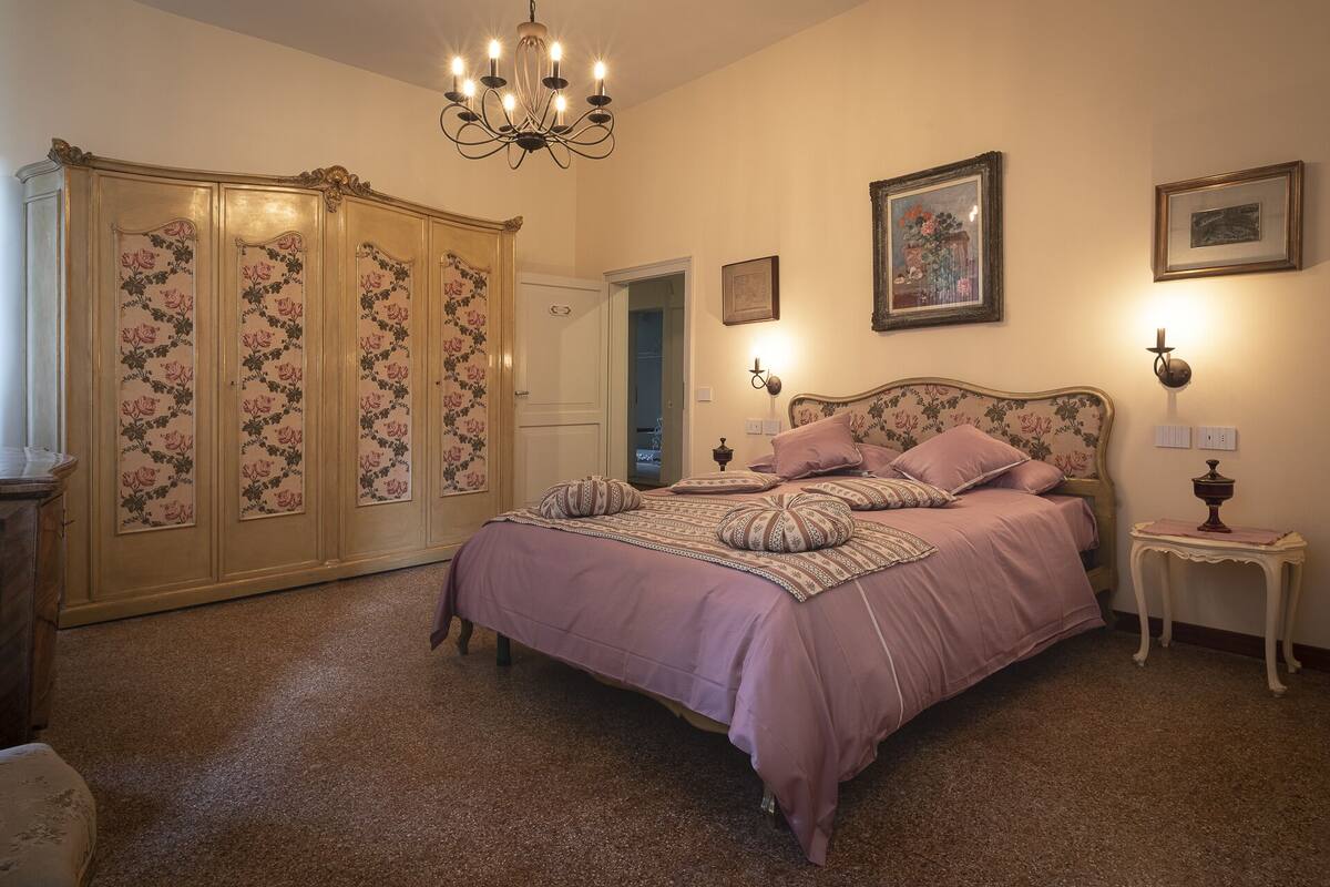 A bedroom with a large bed, a wardrobe, and a chandelier.