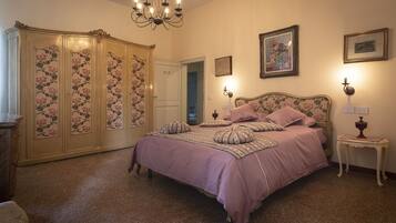 A bedroom with a large bed, a wardrobe, and a chandelier.