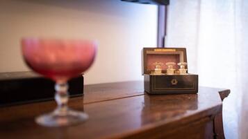 Ein Holztisch mit einem Glas Rotwein und einer kleinen, dunkel gefärbten Schmuckschatulle mit Schlüsselloch.