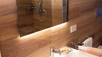 A modern bathroom with a glass-enclosed shower, a white sink, and wooden wall tiles.