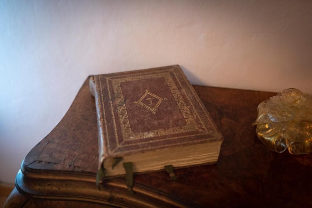 An old book with a decorative cover on a wooden table.