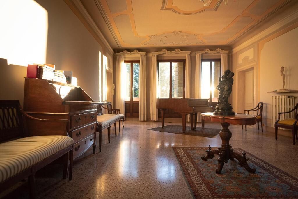 A spacious room with a piano, a sofa, and a statue.