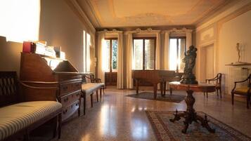 A spacious room with a piano, a sofa, and a statue.