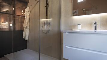 Une salle de bain moderne avec une douche à parois de verre, un meuble-lavabo blanc avec un miroir et une serviette accrochée au mur.