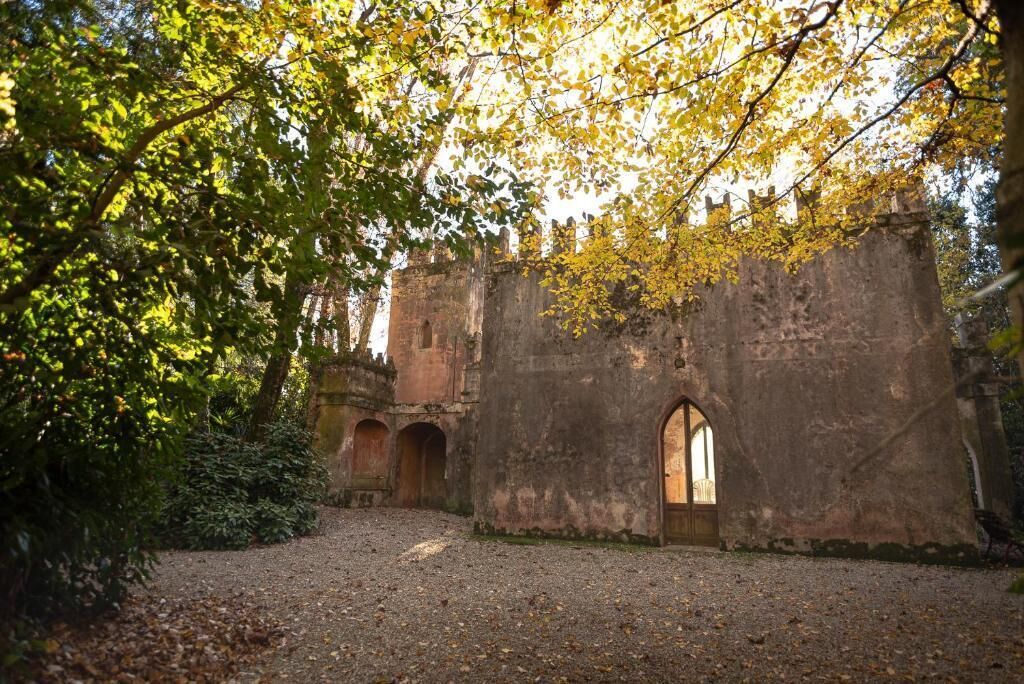 An old stone building with arched doorways and a gravel path leading to it.