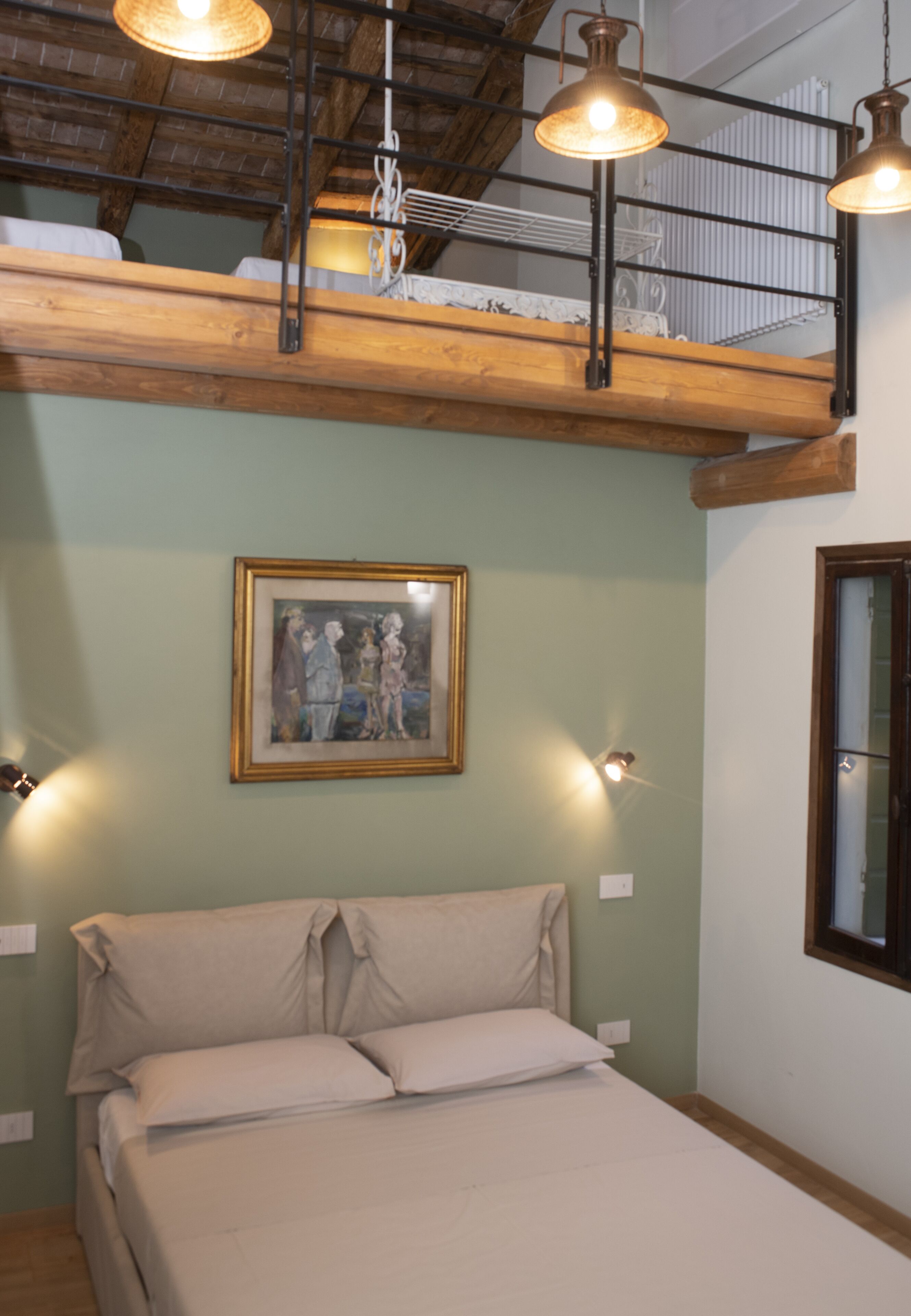 A bedroom with a bed, a painting on the wall, and two pendant lights.