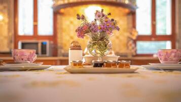 A table with a floral centerpiece, two teacups, and a plate of pastries.