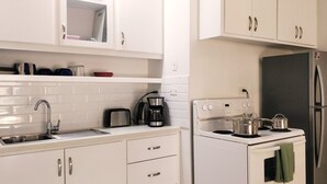 Una cocina moderna con armarios blancos, un refrigerador de acero inoxidable, estufa y pileta.