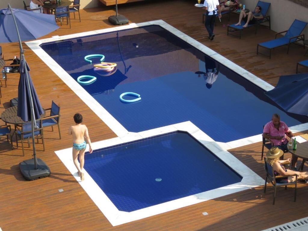 Una piscina al aire libre, sombrillas, sillones reclinables de piscina