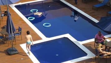 Una piscina al aire libre, sombrillas, sillones reclinables de piscina