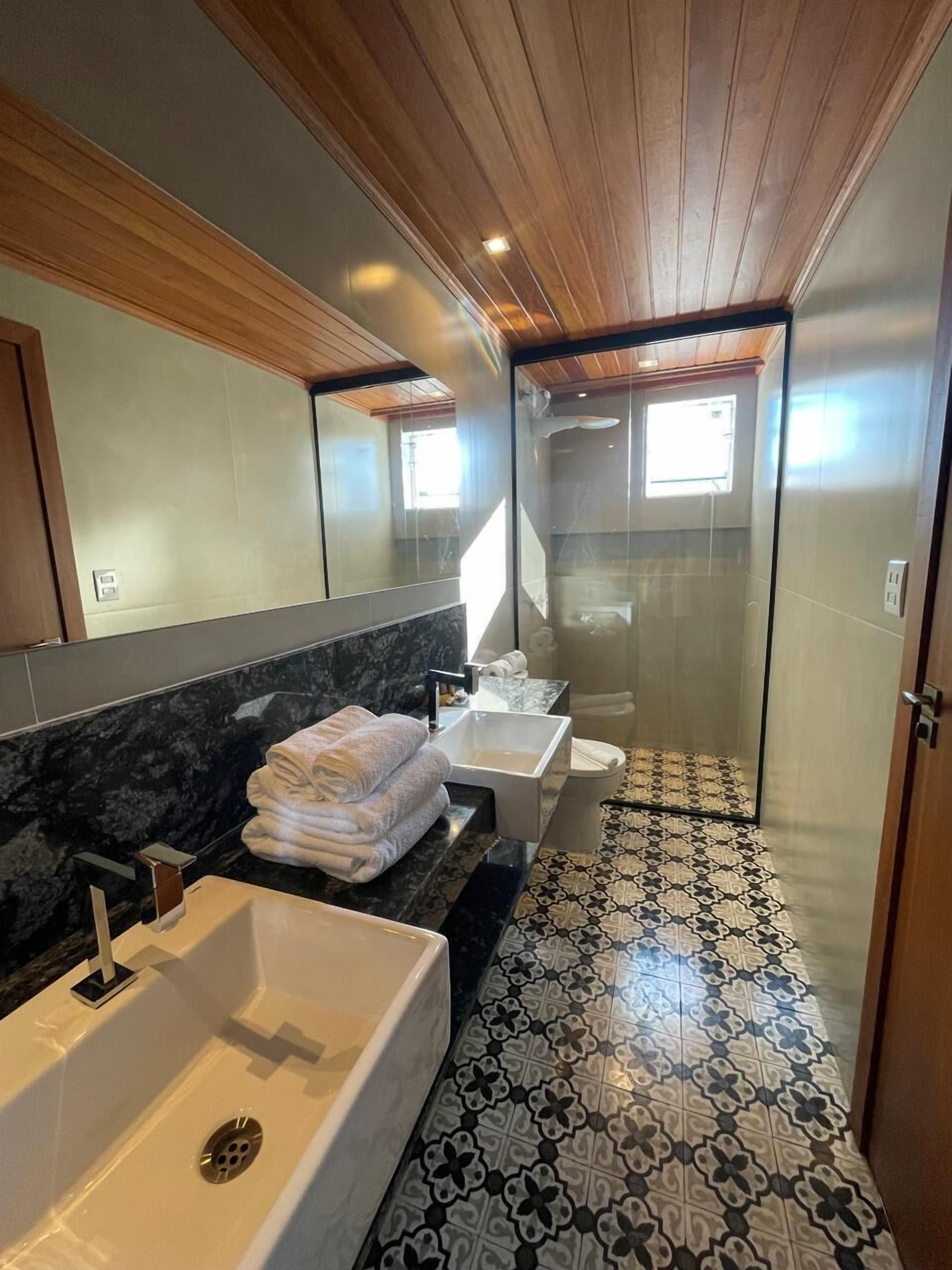 A modern bathroom with a large bathtub, two sinks, and a glass shower enclosure.