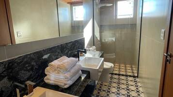Un baño moderno con una bañera grande, dos lavamanos y una mampara de cristal.