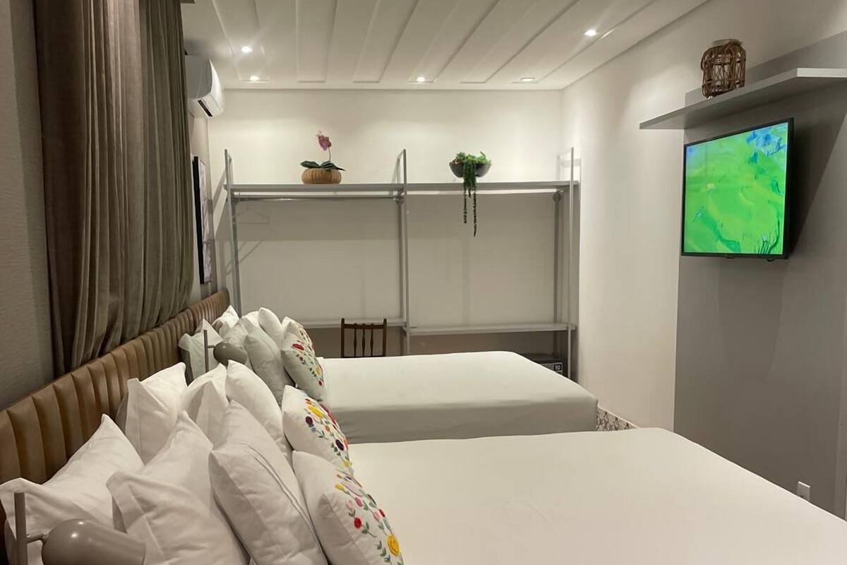 Une chambre moderne avec deux lits, une télévision et une petite table.
