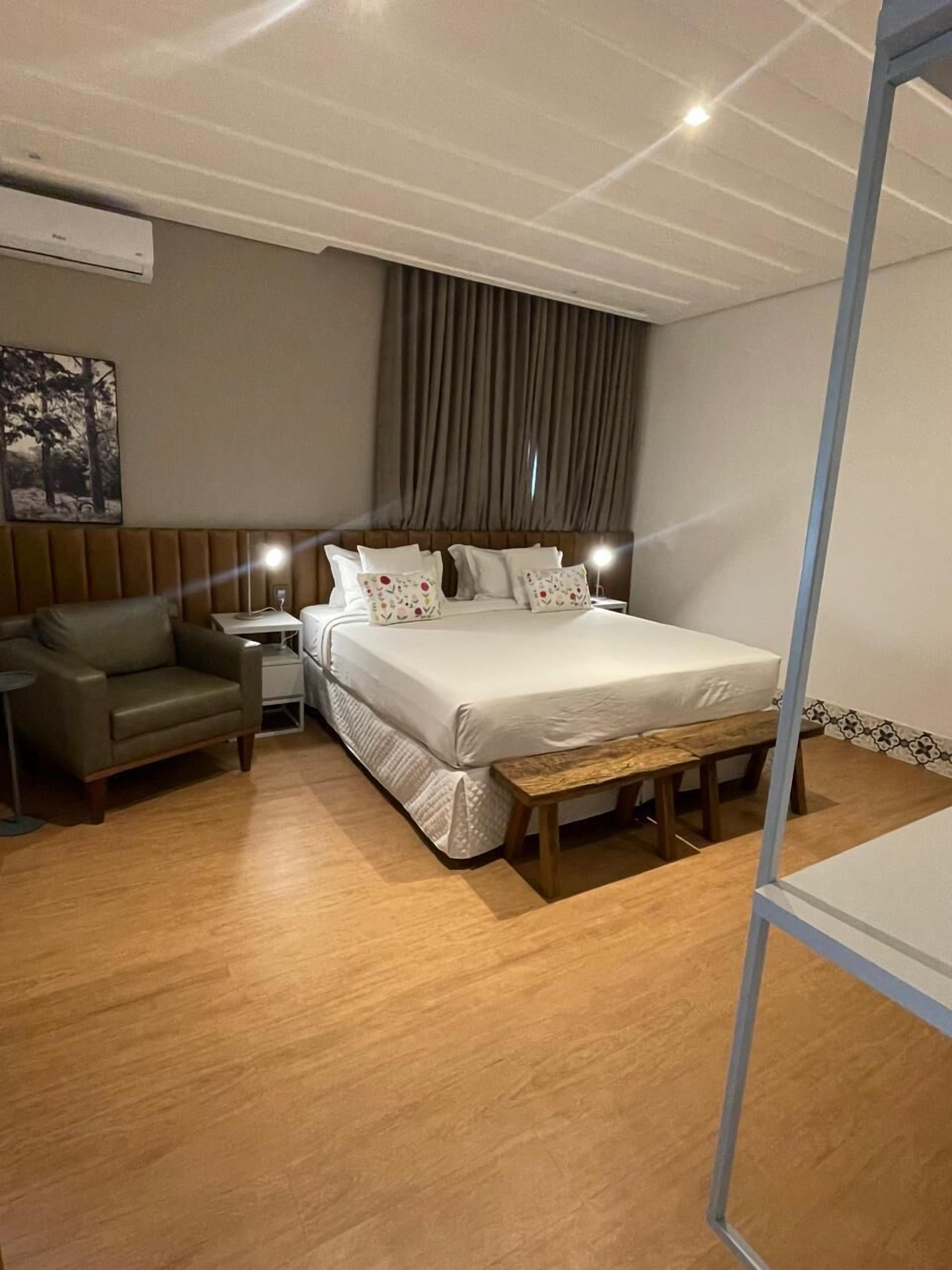 Ein Hotelzimmer mit Bett, Sofa, Nachttisch und Lampe.