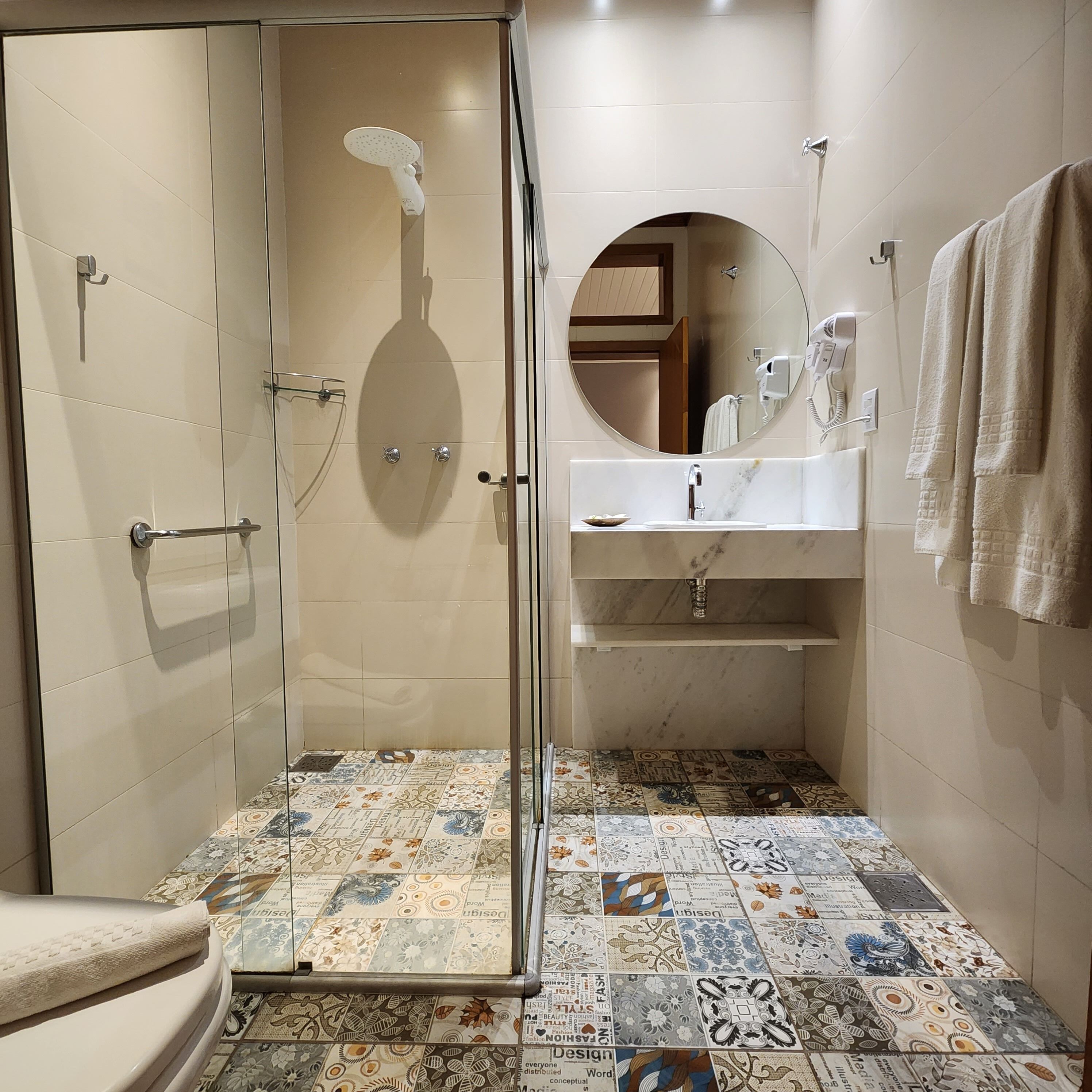 Et badeværelse med brusebad, toilet, vask og spejl.