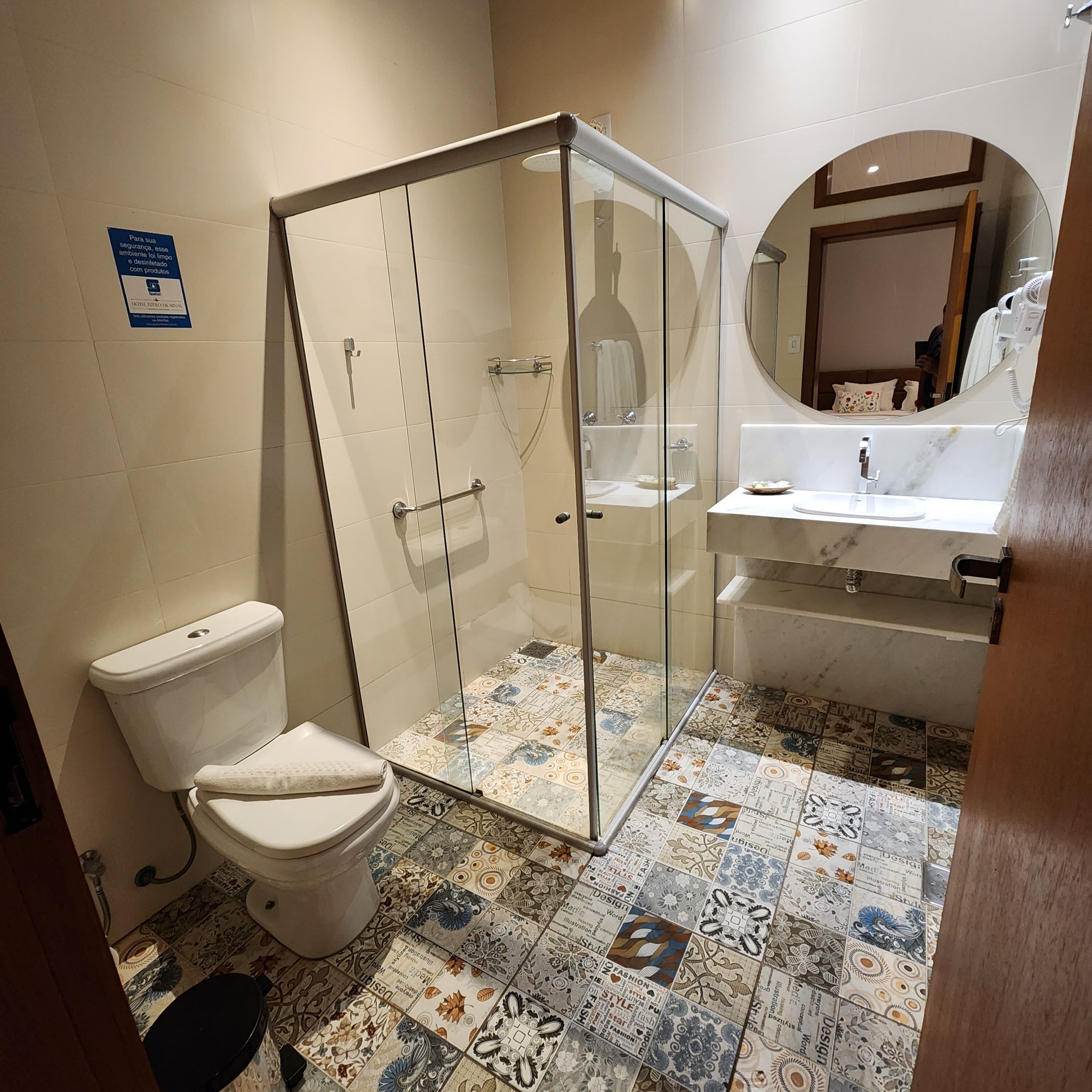 A bathroom with a glass shower enclosure, a toilet, and a sink with a mirror above it.