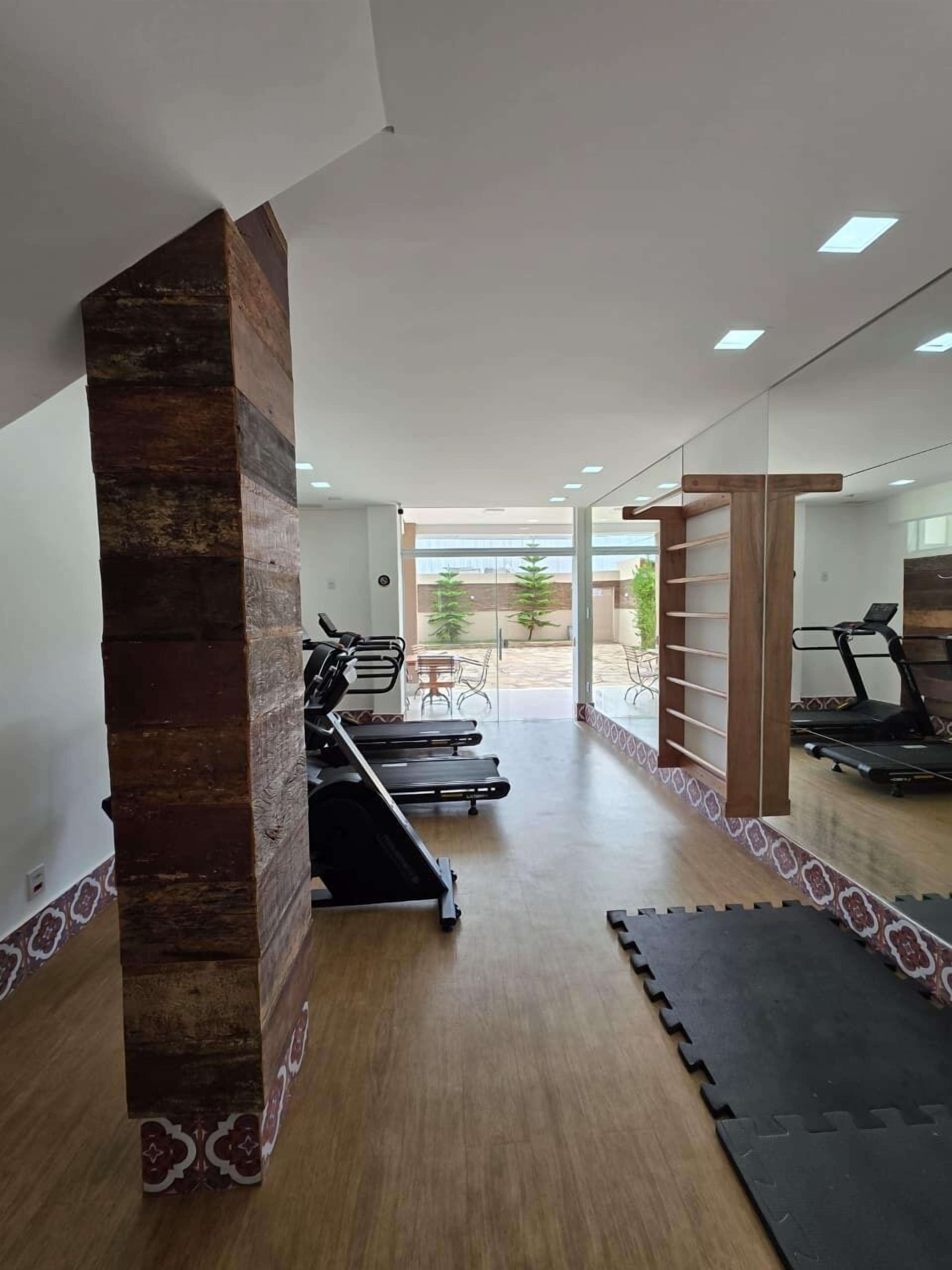 Un gimnasio con cintas de correr, bicicletas estáticas y un espejo grande.