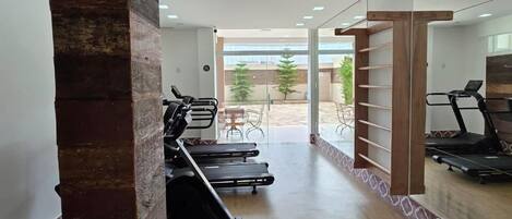 Un gimnasio con cintas de correr, bicicletas estáticas y un espejo grande.