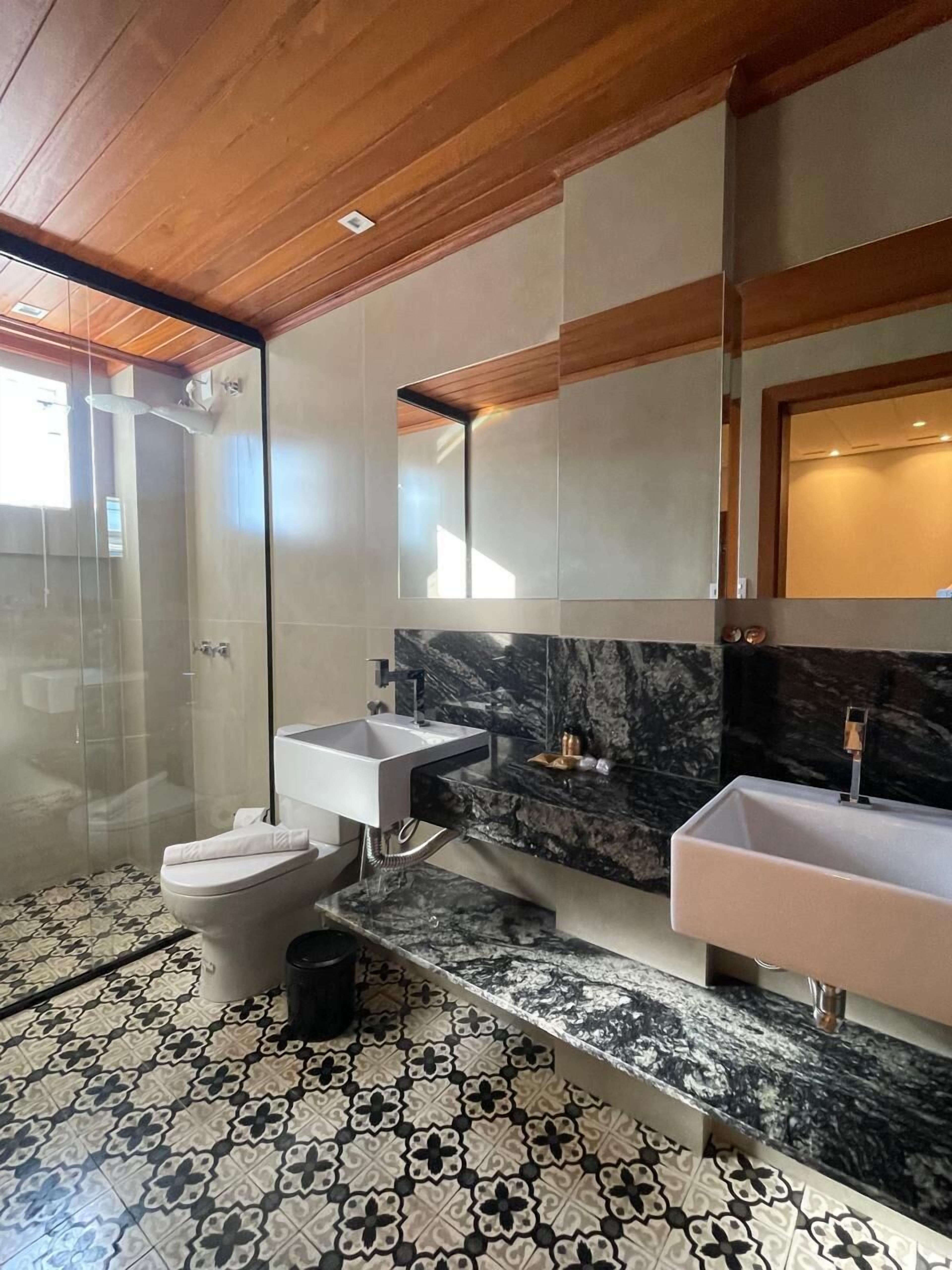 A modern bathroom with a shower, two sinks, and a toilet.
