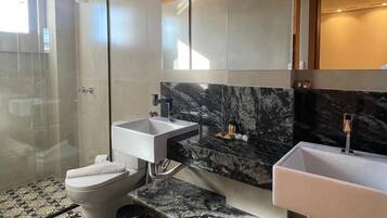A modern bathroom with a shower, two sinks, and a toilet.