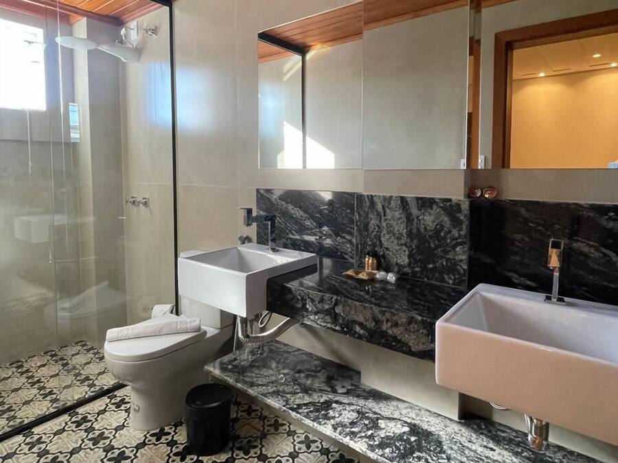 A modern bathroom with a shower, two sinks, and a toilet.