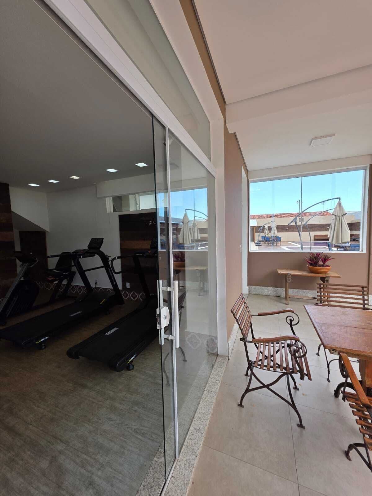 A gym with treadmills and a glass door leading to a balcony with a view.