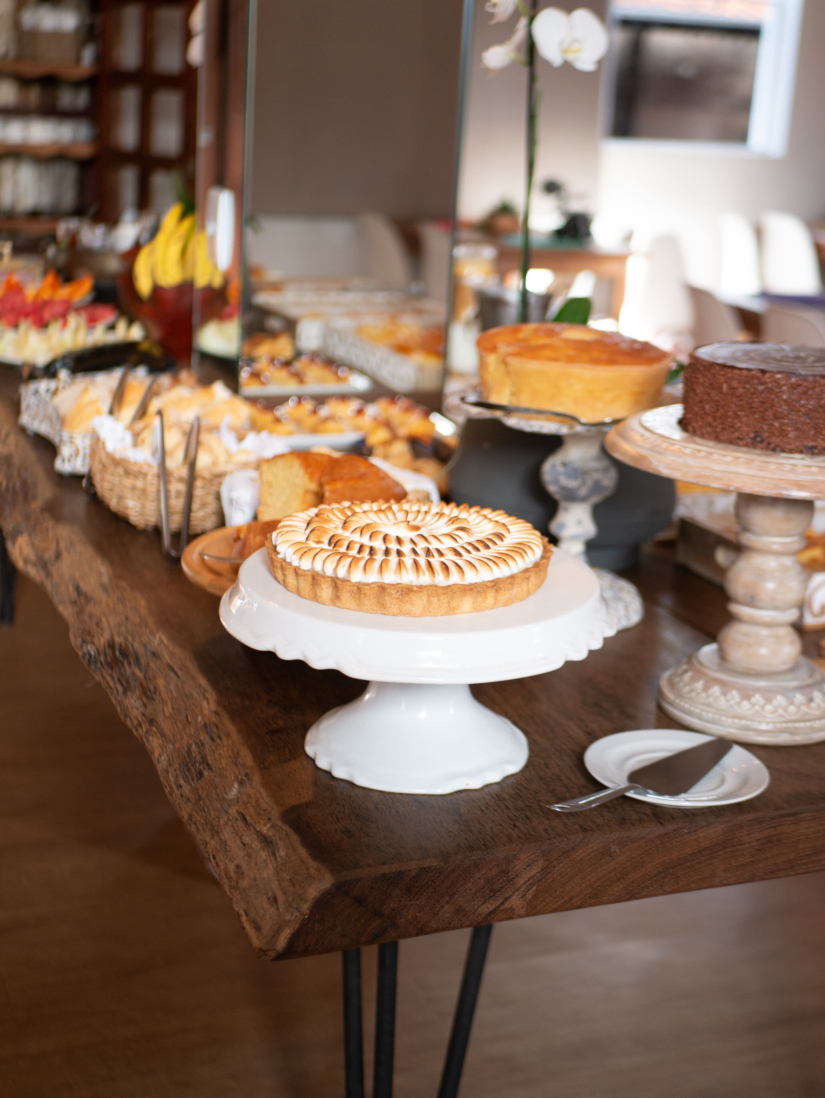 A buffet table with various desserts and a white cake on a pedestal.